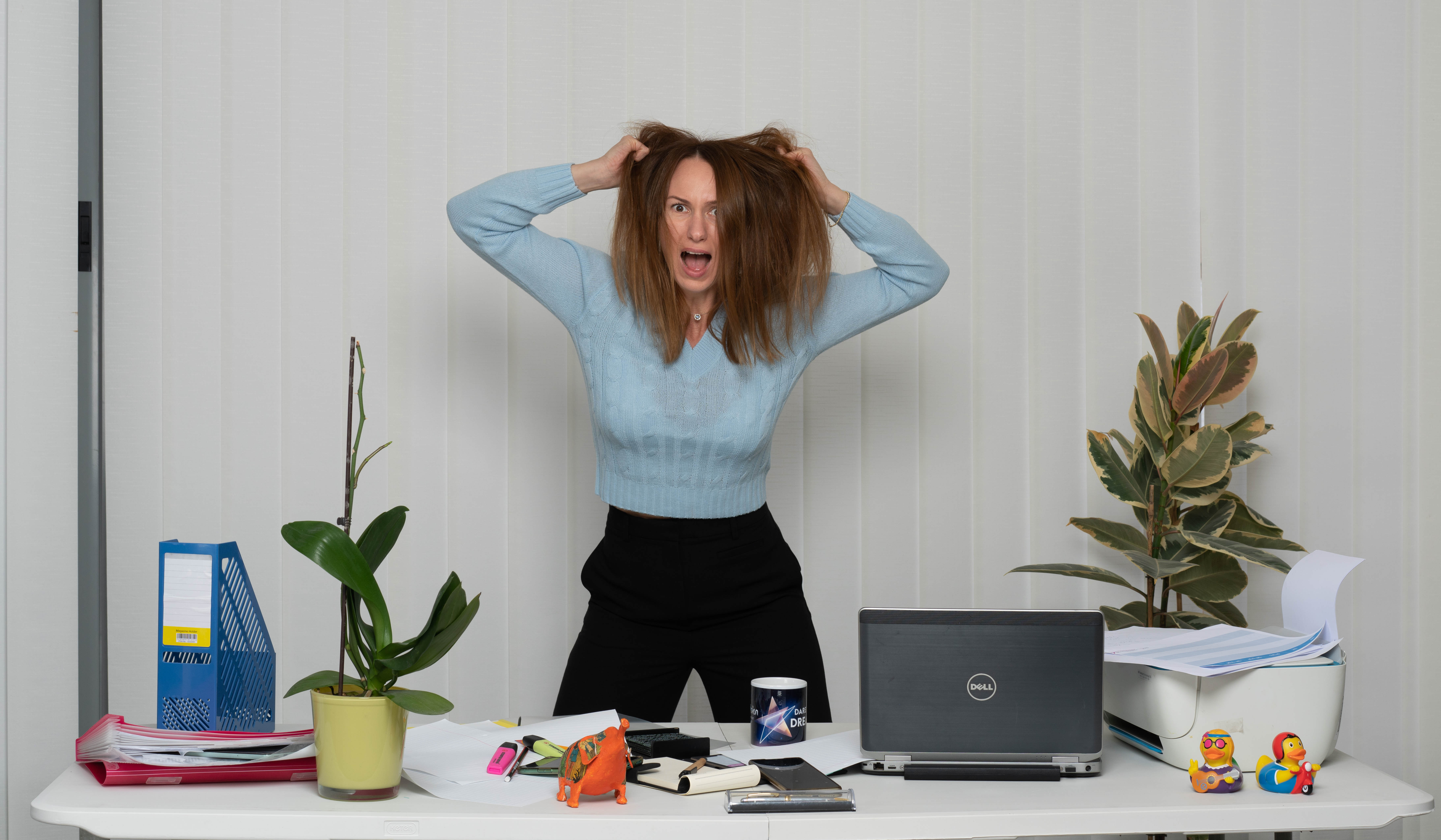 מצולמת מחזיקה את הראש על רקע שולחן משרדי