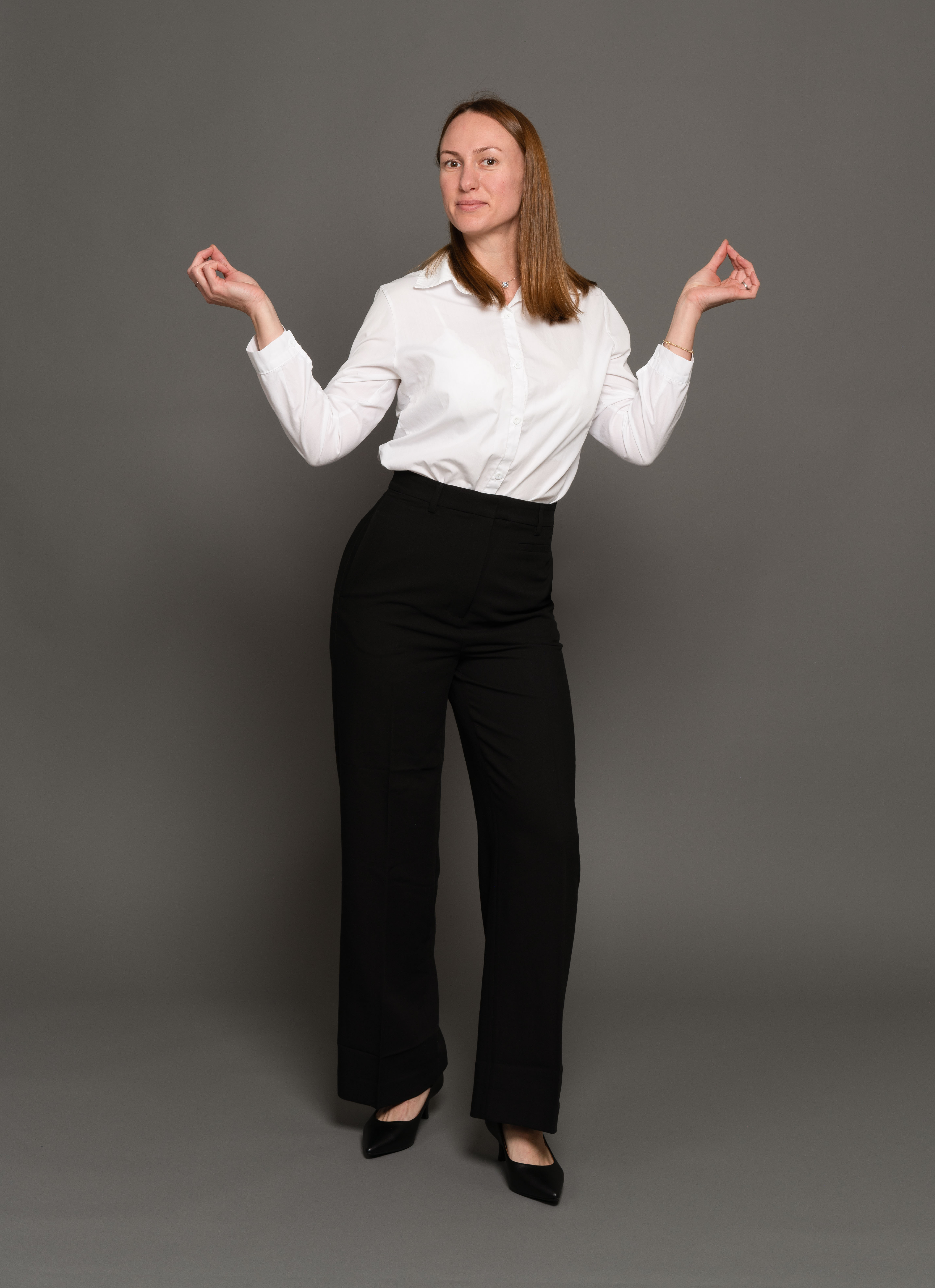 מצולמת עם מכנס שחור וחולצה לבנה על רקע כהה