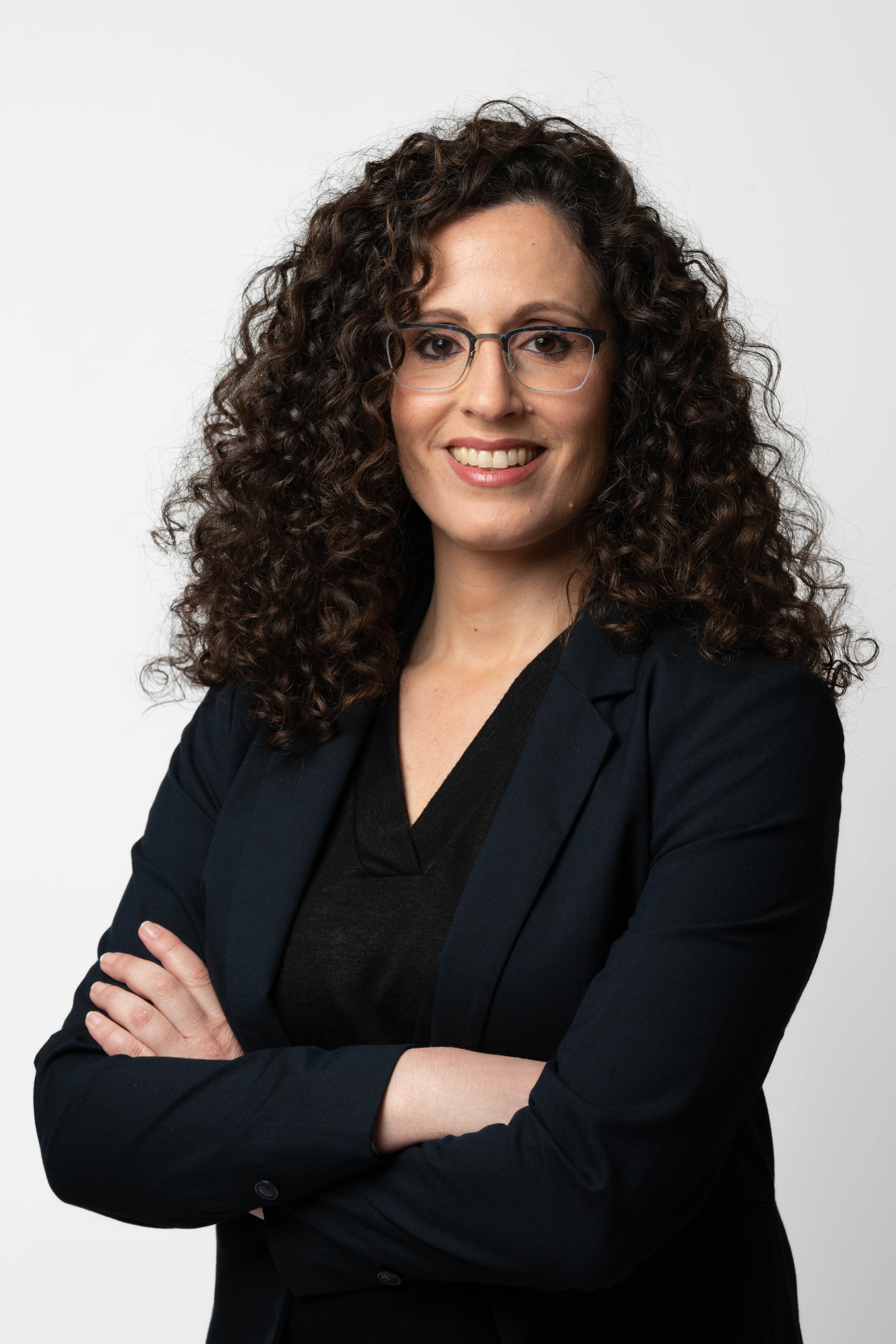 מצולמת עם תלתלים משלבת ידיים על רקע לבן